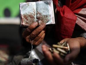 An Egyptian supporter of deposed president Mohamed Morsi holds a copy of the Koran stained with blood and empty casing as he attends a rally in support of the former Islamist leader (AFP)