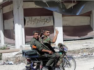 Syrian government forces flash the sign for victory as they patrol in the al-Khalidiyah district of Syria's central city of Homs by motorbike (AFP/JOSEPH EID)