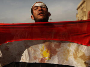 متظاهر يحمل علما ملطخا بالدماء
