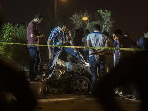 Egyptian officials inspect the wreckage of a car bomb that exploded in a Cairo suburb after Egypt's deputy prosecutor general drove by late on September 29, 2016, wounding a passerby. (AFP/Khaled Desouki)