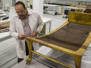 Egyptian archaeologist Medhat Abdallah cleans a gold-plated bed from Tutankhamen's treasures at the new Grand Egyptian Museum near the Giza pyramids in Cairo. (AFP)