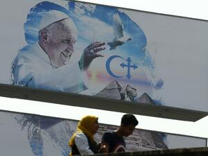 Egyptians walk past a welcome banner bearing a portrait of Pope Francis a day ahead of his visit to the capital Cairo, on April 27, 2017. (AFP/Mohamed El-Shahed)