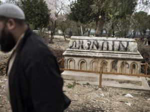 A Muslim man walks past a tomb vandalised with spray paint with a graffiti reading in Hebrew: “Mohammed (prophet) is Dead” at the Mamun Allah cemetery, an old Muslim cemetery in Jerusalem. (AFP/File) 