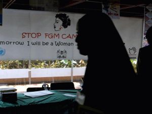 A young woman walks past a banner against female genital mutilation (FGM) at a conference in Nairobi (AFP)
