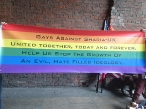 'Gays Against Sharia - UK' organizers hold up a rainbow flag during a march in Manchester (Photo: Twitter @EnglishTommy1)