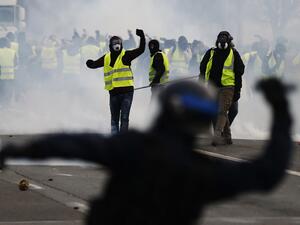 Protestors wearing a yellow vest (gilet jaune), clash with French riot police during a demonstration against rising costs of living they blame on high taxes in Mondeville near Caen. (AFP)