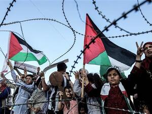 A girl raises a Palestinian flag as another Palestinian boy holds a wooden key symbolizing the return before the barbed-wire east of Gaza City on May 13, 2018. (AFP/ File Photo)