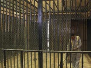 عامل نظافة يباشر عمله داخل قفص الاتهام الذي اعد لمحاكمة مبارك داخل اكاديمية الشرطة بالقاهرة 