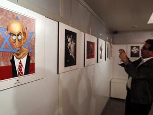 An Iranian man takes a photo of an anti-Israel cartoon displayed at the second international exhibition of drawing and cartoons on the Holocaust in Tehran on May 14, 2016. (AFP/Atta Kenare)
