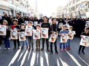 Iranian boys hold images of one of the victims Mohammad Taha Eghdami, 4, during a public funeral ceremony for those killed during an attack on a military parade on the weekend. (ATTA KENARE / AFP)