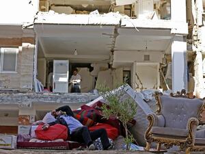 A man rests in the ruins of his home in Kermanshah province following Sunday's deadly earthquake (Atta Kenare/AFP)