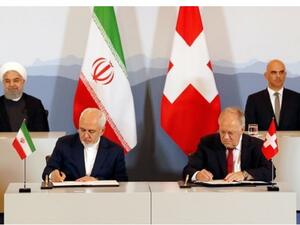 Iranian President Hassan Rouhani (top- L) and Swiss President Alain Berset (top-R) watch as Iranian Foreign Minister Mohammad Javad Zarif (L) and Swiss Economic Minister Johann Schneider-Ammann sign an agreement in Bern on July 3, 2018. (AFP)