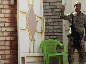 A member of Iraqi government forces flashes the sign of victory as he stands guard during an operation, backed by air support from the US-led coalition, in Fallujah's southern Shuhada neighbourhood to retake the area from the Islamic State (IS) group. (AFP/File)