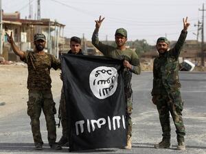 Iraqi members of the Hashed al-Shaabi (Popular Mobilisation Units) carry an upsidedown ISIS flag after victory in the city of al-Qaim (Ahmad Al-Rubaye/AFP)