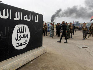 Iraqi security forces and Shiite fighters from the Popular Mobilisation units gather next to a mural depicting the emblem of the Daesh in Tikrit, on 1 April 2015. (AFP/File)