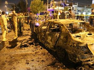 People gather around the incident site as security forces cordon the area after a road-side parked car-bomb attack in Karrada district of Baghdad, Iraq on May 29, 2017. (AFP/Mehmet Hapitoglu)