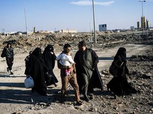 Iraqis walk past a Daesh sign in the newly liberated part of eastern Mosul on January 17, 2017. (AFP/Dimitar Dilkoff)