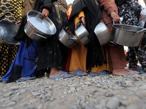 Displaced Iraqis receive aid food during the Muslim holy month of Ramadan at al-Khazir camp for the internally displaced, located between Arbil and Mosul, on June 5, 2017. The camp was hit by a mass outbreak of food poisoning on June 12. (Karim Sahib/AFP)