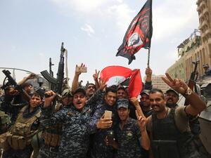 Members of the Iraqi federal police dance and wave their country's national flag in celebration in the Old City of Mosul on July 8, 2017 (Ahmad Al-Rubaye/ AFP)