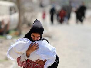 A displaced Iraqi woman carries a baby as she evacuates from western Mosul's Zanjili neighbourhood on June 1, 2017 during ongoing battles between Iraqi forces to retake the city from Daesh fighters. (Karim Sahib/AFP)