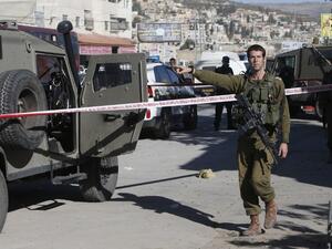 Israeli security forces check the site where a Palestinian man stabbed an Israeli soldier with a screwdriver before being shot and wounded, near the entrance to Hawara, south of the city of Nablus, on November 9, 2016. (AFP/Jaafar Ashtiyeh)