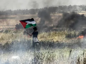 A Palestinian boy holds his national flag during clashes with Israeli security forces on the Gaza-Israel border. (AFP/ File Photo)