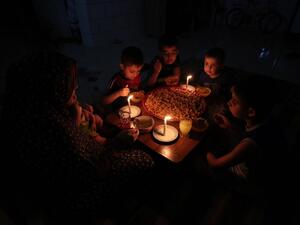 A Palestinian family eats dinner by candlelight at their makeshift home in the Rafah refugee camp, in the southern Gaza Strip, during a power outage on June 11, 2017. (Said Khatib/AFP)