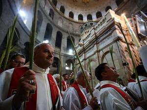 Catholic priests hold palm branches as they circle the aedicule during the Palm Sunday Easter procession at the Church of the Holy Sepulchre in Jerusalem's Old City on April 9, 2017. (AFP/Gali Tibbon)