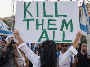 An Israeli woman holds up a sign with 'Too many terrorists in prison' on one side and 'Kill them all!' on the other - in reference to Palestinians. (AFP/File)