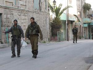 Israeli soldiers walk in the West Bank city of Hebron, where children as young as 13 were detained this morning. (AFP/File)