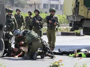 Israeli security forces tend to an injured soldier next to the body of a slain Palestinian in the southern occupied West Bank. (AFP/ File)