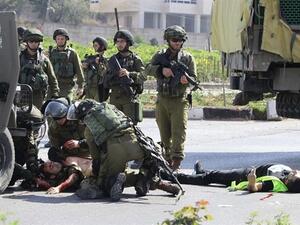 Israeli security forces tend to an injured soldier next to the body of a slain Palestinian in the southern occupied West Bank. (AFP/ File)