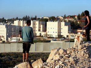 Palestinians in the Jalazone refugee camp in the West Bank look out at a wall surrounding an Israeli settlement. (AFP/File)