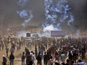 Palestinians run for cover from tear gas during clashes with Israeli security forces near the border between Israel and the Gaza Strip, east of Jabalia/AFP