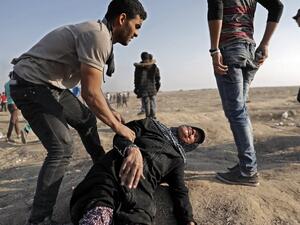 A Palestinian youth tends to a fallen old lady affected by tear gas during clashes with Israeli forces east of Gaza City /AFP