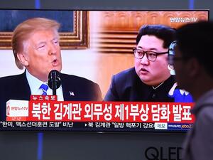 A man walks past a television news screen showing North Korean leader Kim Jong Un and US President Donald Trump/AFP