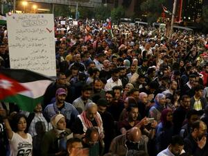 Demonstrators wave flags and hold signs during a protest in Amman, Jordan, near the prime minister's office, June 4, 2018. Protestors have demonstrated for the fifth night against the new proposed income tax draft law and other anti-austerity measures. Khalil Mazeraawi/ AFP) 
