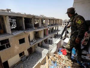A member of the Kurdish People's Protection Units (YPG), which Ankara deems to be a terror group, moves through destroyed buildings in Raqa on July 28, 2017 (AFP)