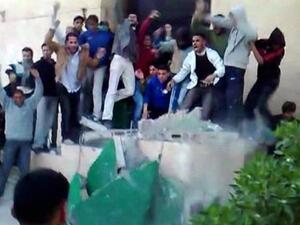متظاهرون ليبيون يسقطون صورة كبيرة للعقيد القذافي في بنغازي
