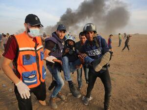 Palestinian paramedics and journalists carry a wounded fellow journalist during clashes with Israeli forces east of Gaza city. (Said KHATIB / AFP)