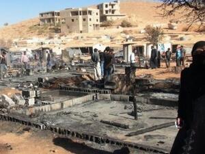 People walk past the charred remains of tents at a refugee camp outside Arsal, Lebanon. (AFP)