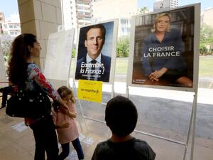 French citizens residing in Lebanon look at the election posters of independent centrist French presidential candidate Emmanuel Macron (L) and far-right Front National (FN - National Front) candidate Marine Le Pen, as they arrive to cast their votes at the French embassy in Beirut on May 7, 2017 during the second round of the French presidential vote. (AFP/Anwar Amro)