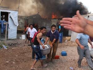 Syrian refugees carry a machine away as fire engulfs an unofficial refugee camp in Lebanon's eastern Bekaa Valley. (AFP)