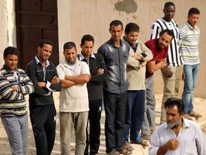 Migrants from Chad, Sudan, Egypt and Bangladesh wait to receive aid distribution provided by the International Organization for Migration (IOM) in cooperation with Libyan Red Crescent in the east of Libya on August 16, 2016. (AFP/Abdullah Doma)