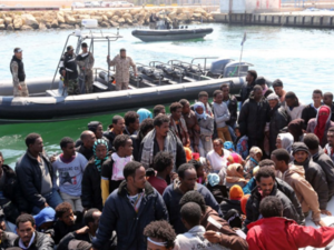 The Libyan coast guard watches over a group of African migrants after towing their boat to the Tripoli shore. (AFP/File)