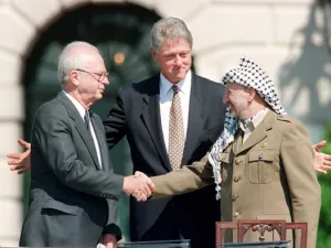 US President Bill Clinton stands between PLO leader Yasser Arafat and Israeli Prime Minister Yitzhak Rabin as they shake hands for the first time, on Sept. 13, 1993 (AFP)