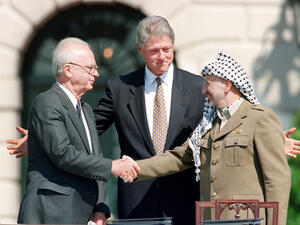 US President Bill Clinton stands between PLO leader Yasser Arafat and Israeli Prime Minister Yitzhak Rabin as they shake hands for the first time, on Sept. 13, 1993 (AFP)