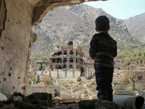 A photo of March 18, 2018, for a Yemeni child looking out at buildings damaged in an air strike in the southern Yemeni city of Taez. (AFP)