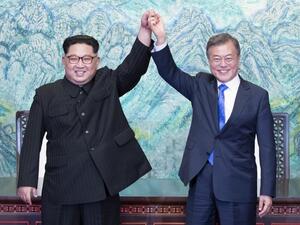 North Korea's leader Kim Jong Un (L) and South Korea's President Moon Jae-in (R) raise their joined hands during a signing ceremony near the end of their historic summit. (AFP/ File Photo)