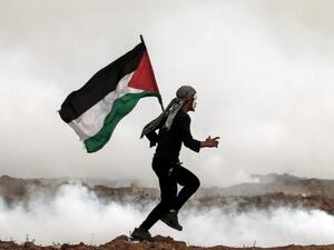 A Palestinian man holds the national flag as he runs through teargas during a protest, on the eastern outskirts of Gaza City, near the border with Israel. (MAHMUD HAMS / AFP) A Palestinian man holds the national flag as he runs through teargas during a protest, on the eastern outskirts of Gaza City, near the border with Israel. (MAHMUD HAMS / AFP)